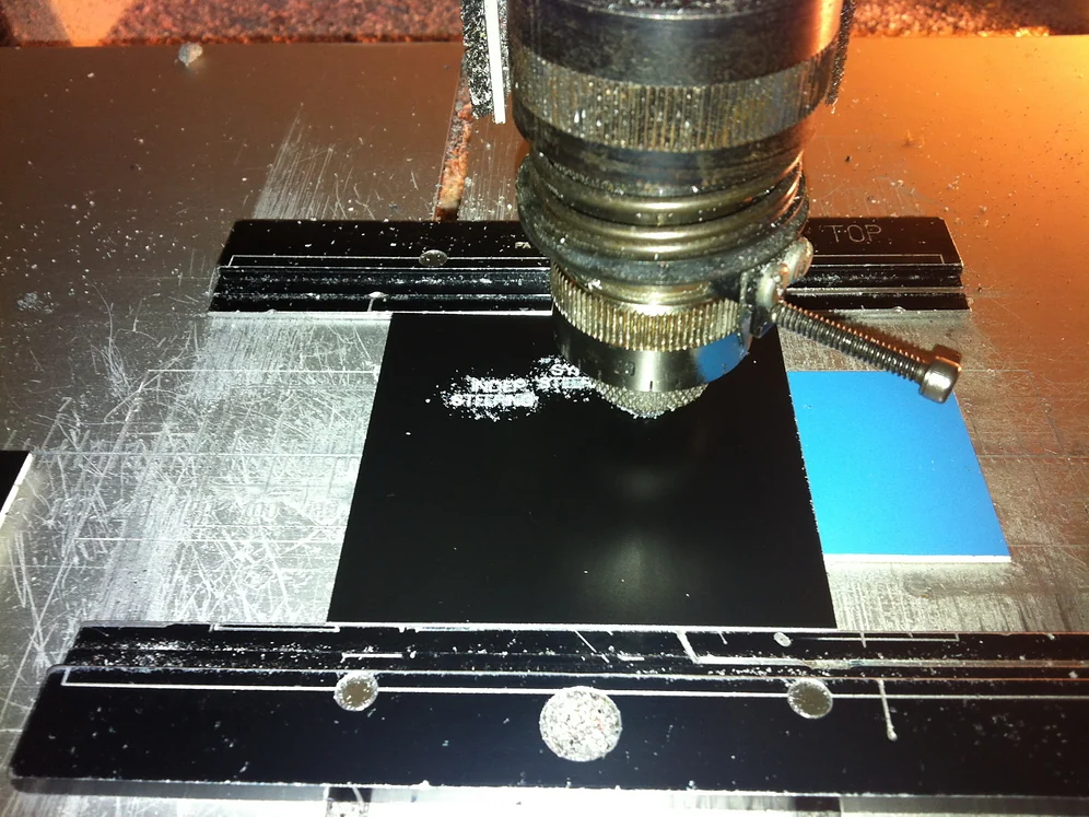 Computerized engraving spindle cutting a black plate in a fixture